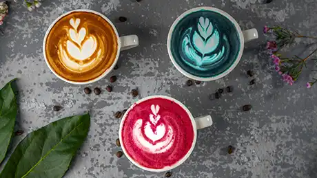 multiple colorful coffee cups with latte art